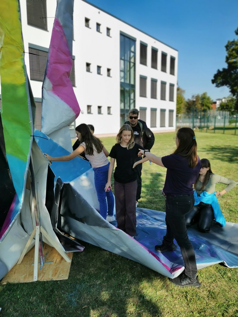Schüler*innen der GMS Puschkin in Oschersleben bemalen ihren zuvor gefalteten XXL Origamikranich (5x8m) für Brüssel