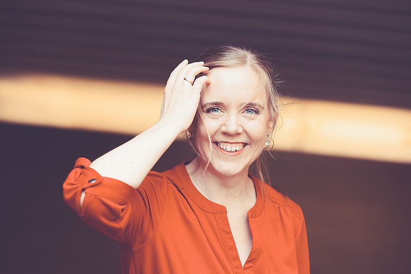 Frau im roten Kleid mit Mikrofon lehnt an Geländer