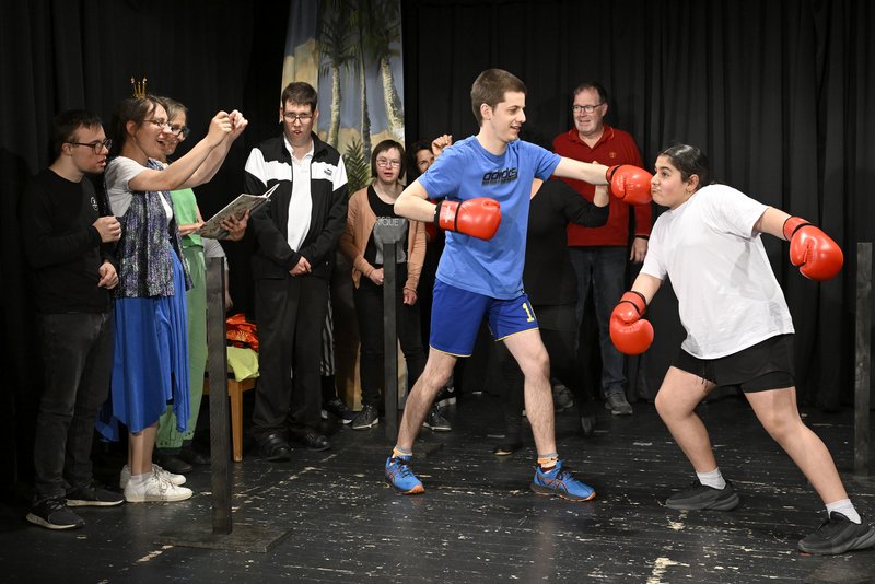 Zwei Schauspielende beim Boxkampf, im Hintergrund Fans und Trainer