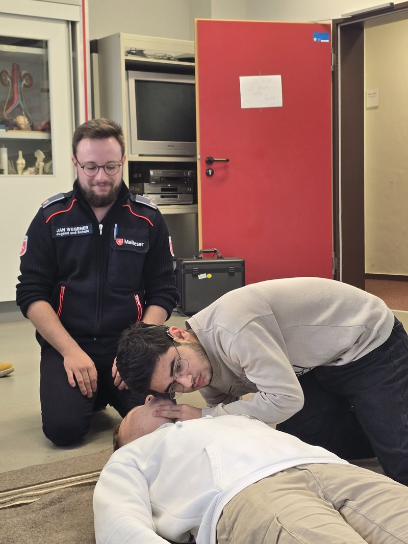 Zwei Schulsanitäter üben die Atemkontrolle einer bewusstlosen Person