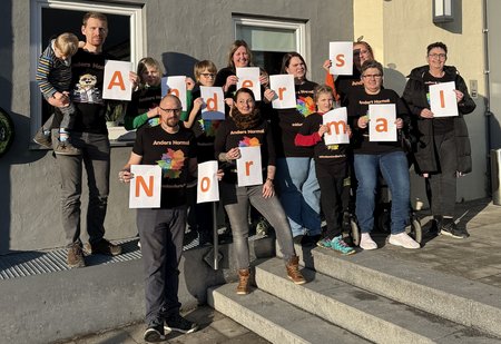 Mehrere Personen halten Buchstaben in die Luft, die zusammen die Worte "Anders Normal" ergeben