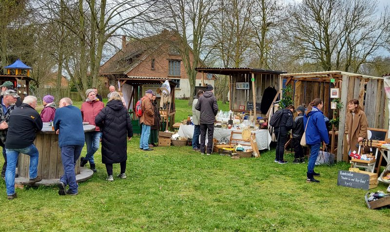 Mehrere Personen stehen auf einer Wiese, es gibt mehrere Stände