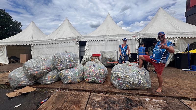 Große Säcke mit Pfanddosen gefüllt und einem motivierten Zukunftsmusik Helfer, der sich freut