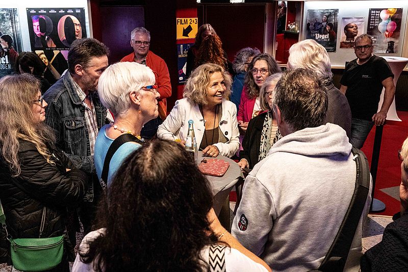 eine Frau spricht mit einem älteren Mann im Kinofoyer