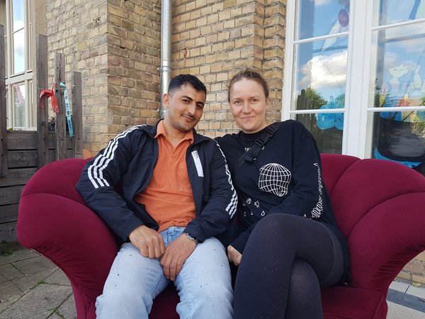 Eine Frau und ein Mann sitzen nach beieinander auf einem Sofa.