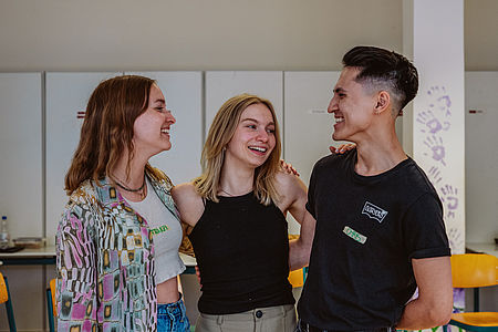 Drei ehrenamtliche Dare2Care Workshopleitungen lächeln sich an (Franziska Schilling, Johanna Gritzbach, Chris Phol)