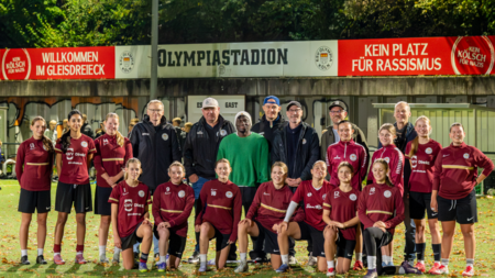 Trainer und Spieler*innen stehen vor den Bannern im Olympiastadion