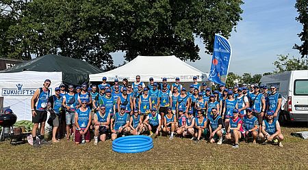 Gruppenbild mit etwa 65 Personen vor einem Zelt