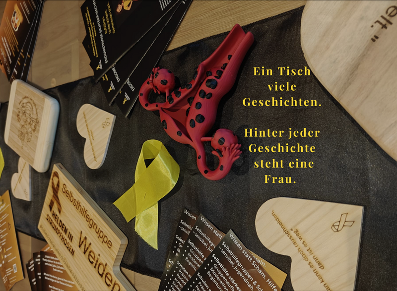 Ein Gruppentisch mit Informationsmaterialien bereitet eine Selbsthilfegruppe von Helden in Strumpfhosen® vor. Das Bild steht für einen geschützten Raum, in dem Betroffene sich vertrauensvoll austauschen und gegenseitig stärken können.