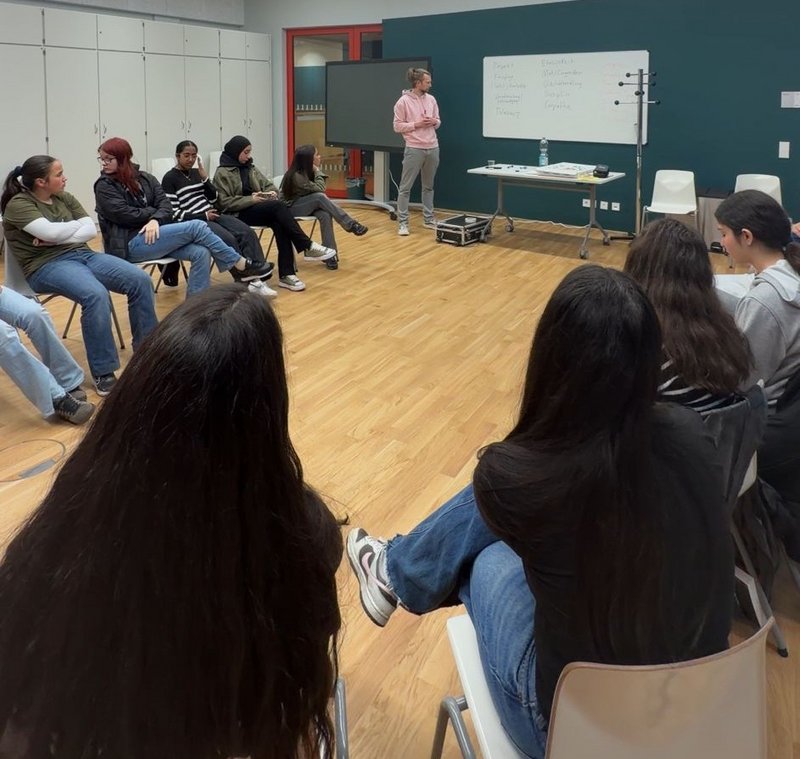 Jugendliche des SV Rhenania Hamborn sitzen während einer Werteschulung im Campus Marxloh im Gesprächskreis. Gemeinsam mit einem Referenten setzen sie sich mit Fairplay, Respekt, Verantwortung und dem Miteinander im Sport auseinander.