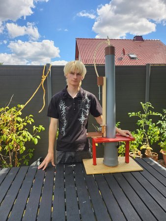Der Projektentwickler steht neben seinem selbst entwickelten Funktionsmodell eines Osmosekraftwerks, das mithilfe von Osmose aus Süß- und Salzwasser erneuerbare Energie erzeugen kann.