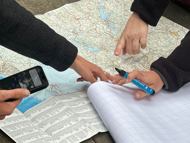 Menschen zeigen mit Stiften auf eine Landkarte