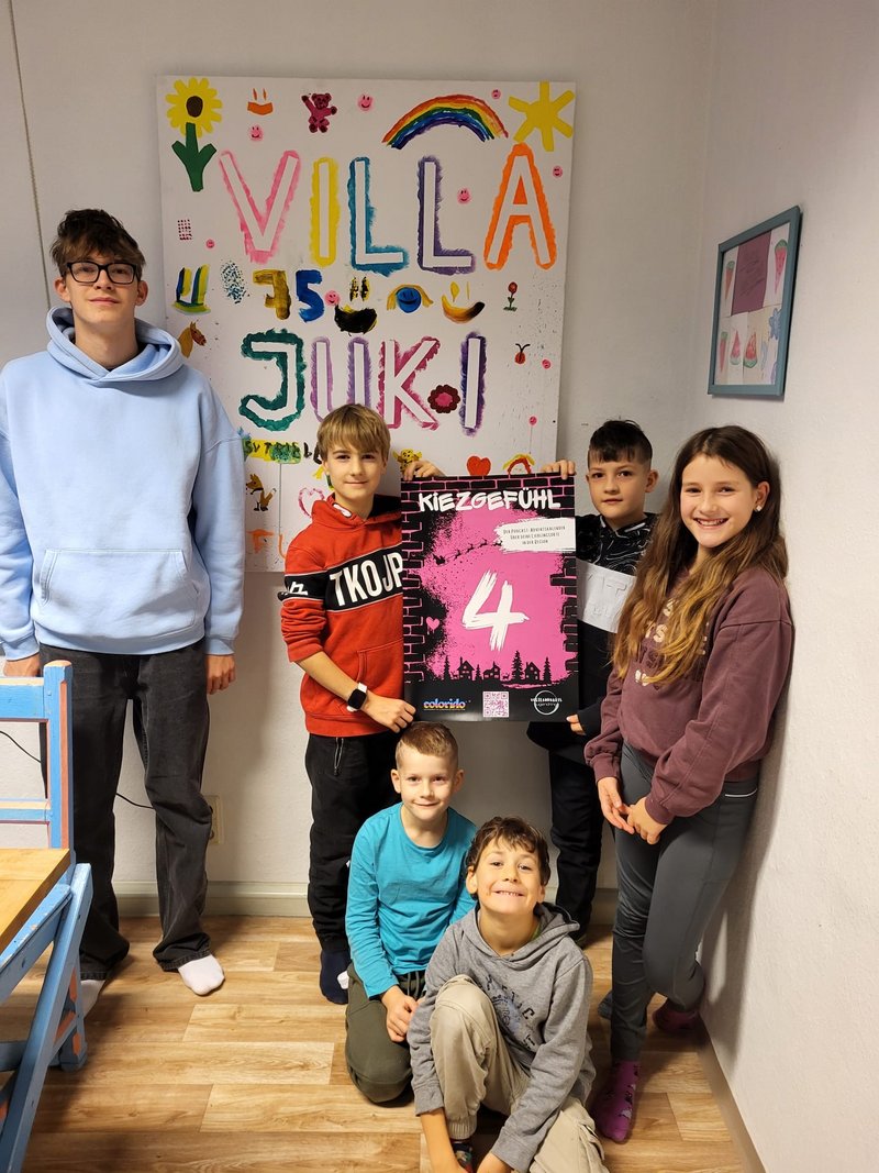 Jugendliche präsentieren in der Villa JuKi das Plakat ihres Podcast.
