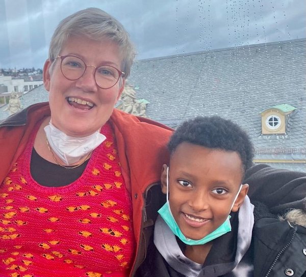 Eine Frau steht mit einem Kind im Arm nebeneinander. Beide lachen in die Kamera.