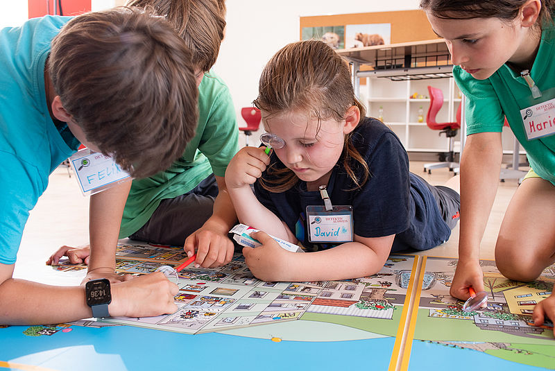 Grundschulkinder als Detektive mit Wimmelbild
