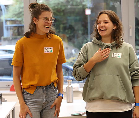 Zwei Frauen stehen nebeneinander und lachen