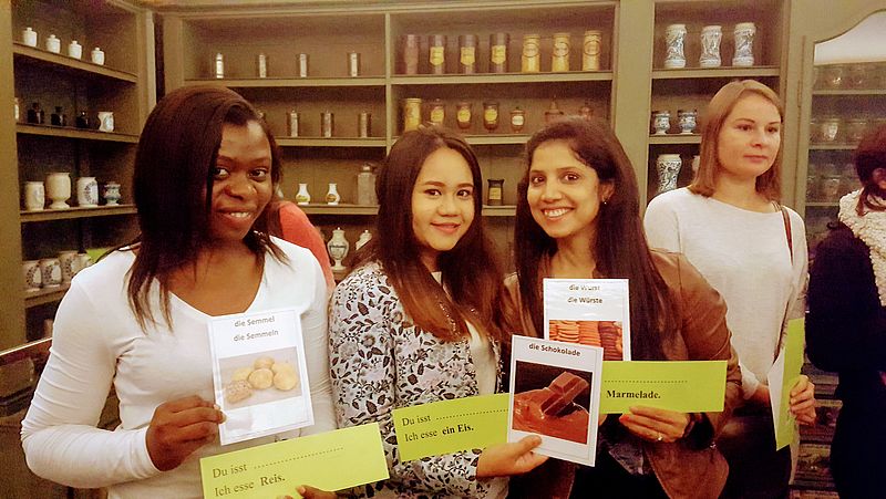 Vier Frauen stehen im Ausstellungsraum eines Museums und halten Vokabelkarten