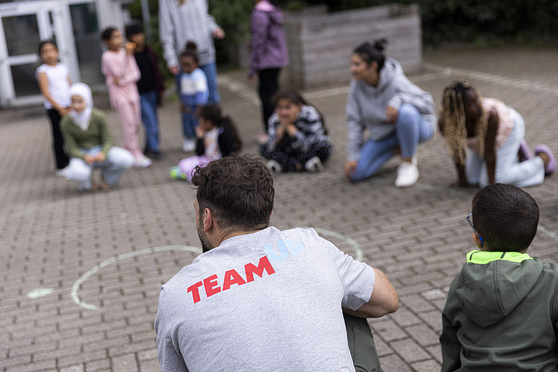 Kinder rund um ein Sprungtuch mit Ehrenamtlichen