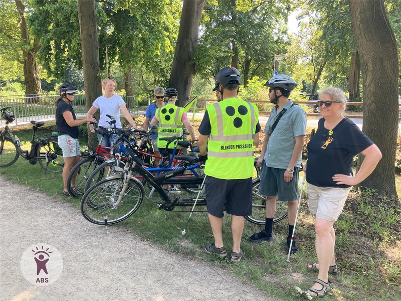 Blinde mit Warnweste und Piloten vor ihren Tandems