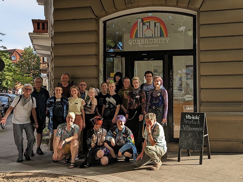 Junge queere Menschen stehen mit alten queeren Menschen vor unserem Jugendzentrum