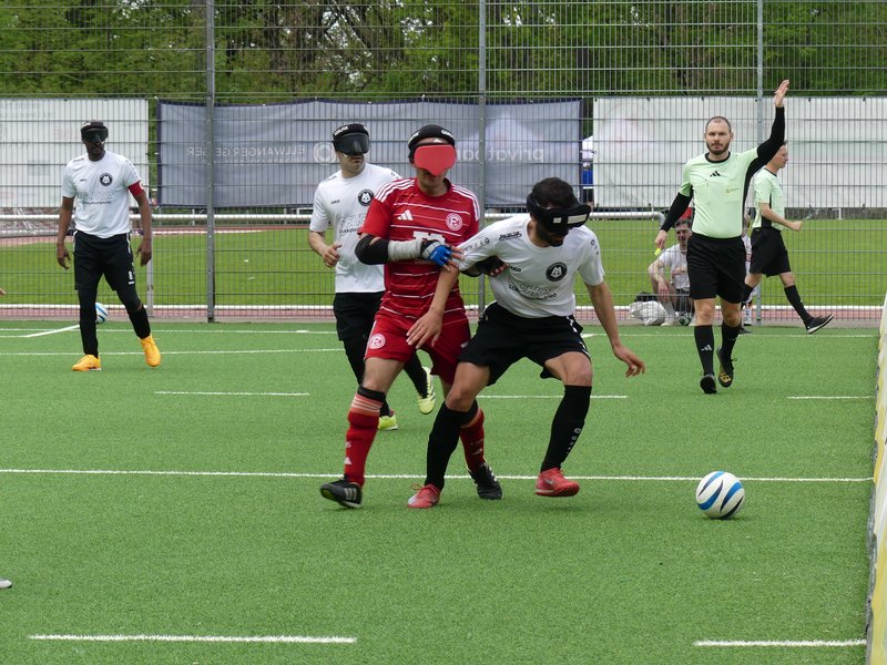 Im Zentrum des Bildes verteidigt ein Blindenfußballer des MTV den Ball gegen einen Düsseldorfer Spieler
