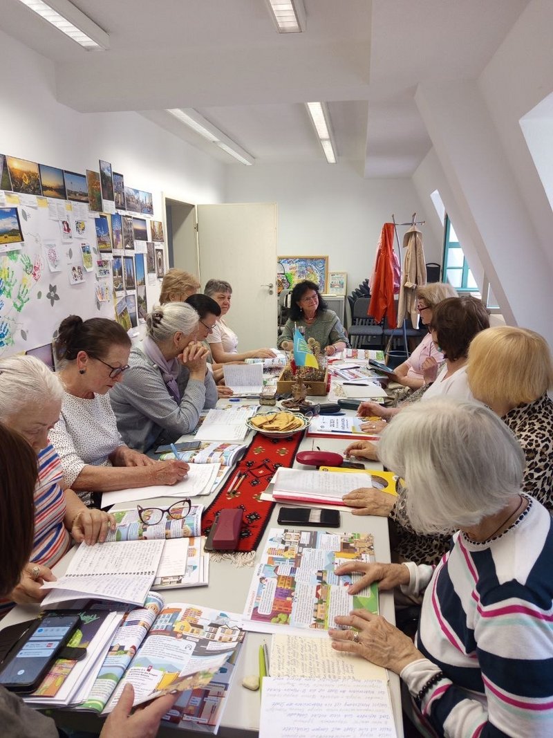 Teilnehmende des Sprachclubs von Save Ukraine e.V. sitzen gemeinsam an einem Tisch und lernen Deutsch in einer Gruppenveranstaltung.