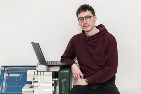 Matteo Ramin neben einem Laptop und verschiedenen Verleih-Gegenständen