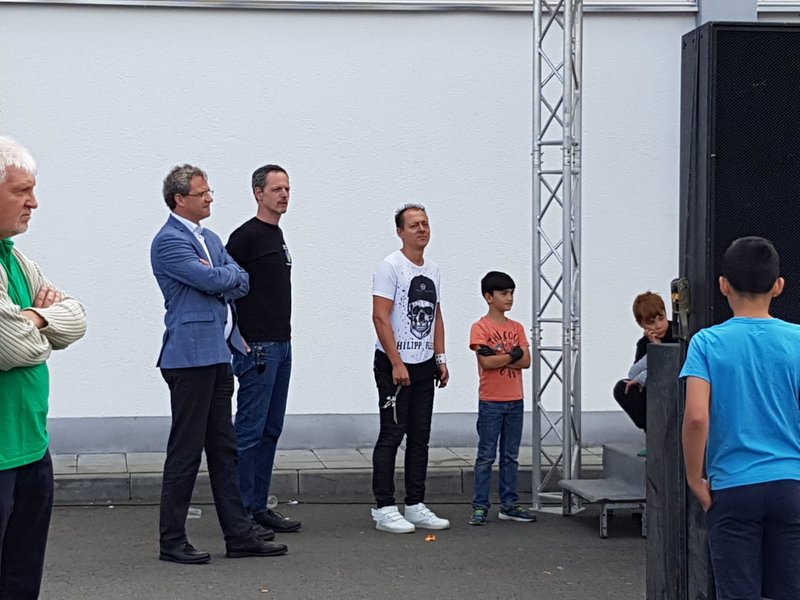 Vier Menschen stehen neben einer Bühne und warten auf ihren Auftritt bei der Eröffnung des Stadtteilfests
