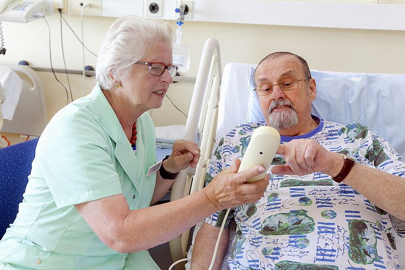Grüne Dame im Krankenhaus unterstützt Patienten auf dem Weg zur Untersuchung