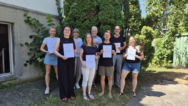 Eine Gruppe von MANO-Berater*innen zeigt stolz ihre Zertifikate.