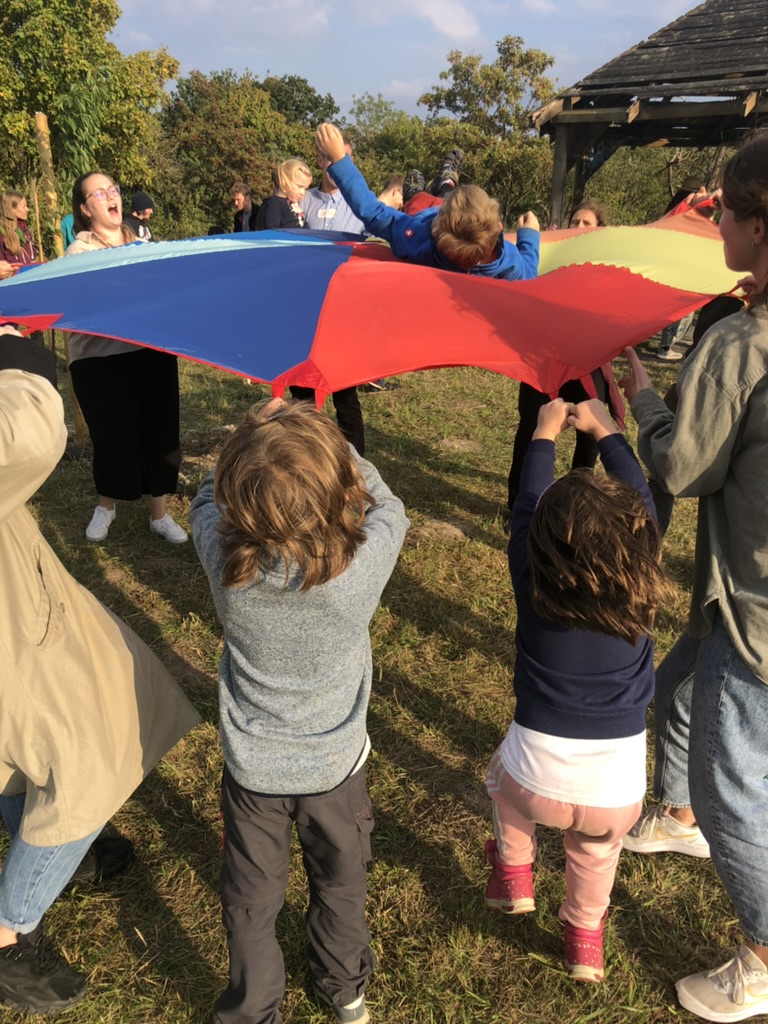 Menschen halten ein Kind in einem Tuch und lassen es hochleben.