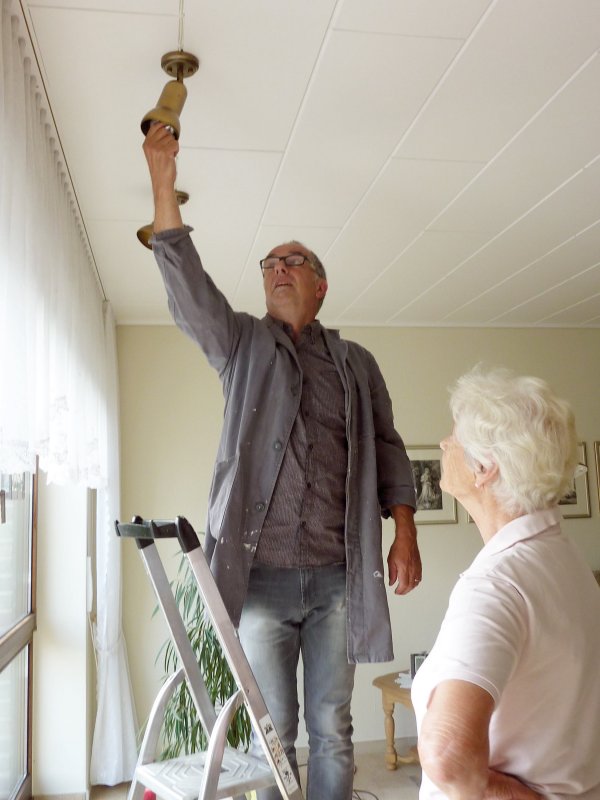 Ein Ehrenamtlicher von ANTI ROST Münster wechselt bei einer Seniorin ein Leuchtmittel, während sie den Einsatz begleitet.