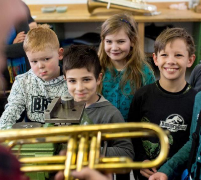 Kinder schauen fasziniert auf ein Musikinstrument